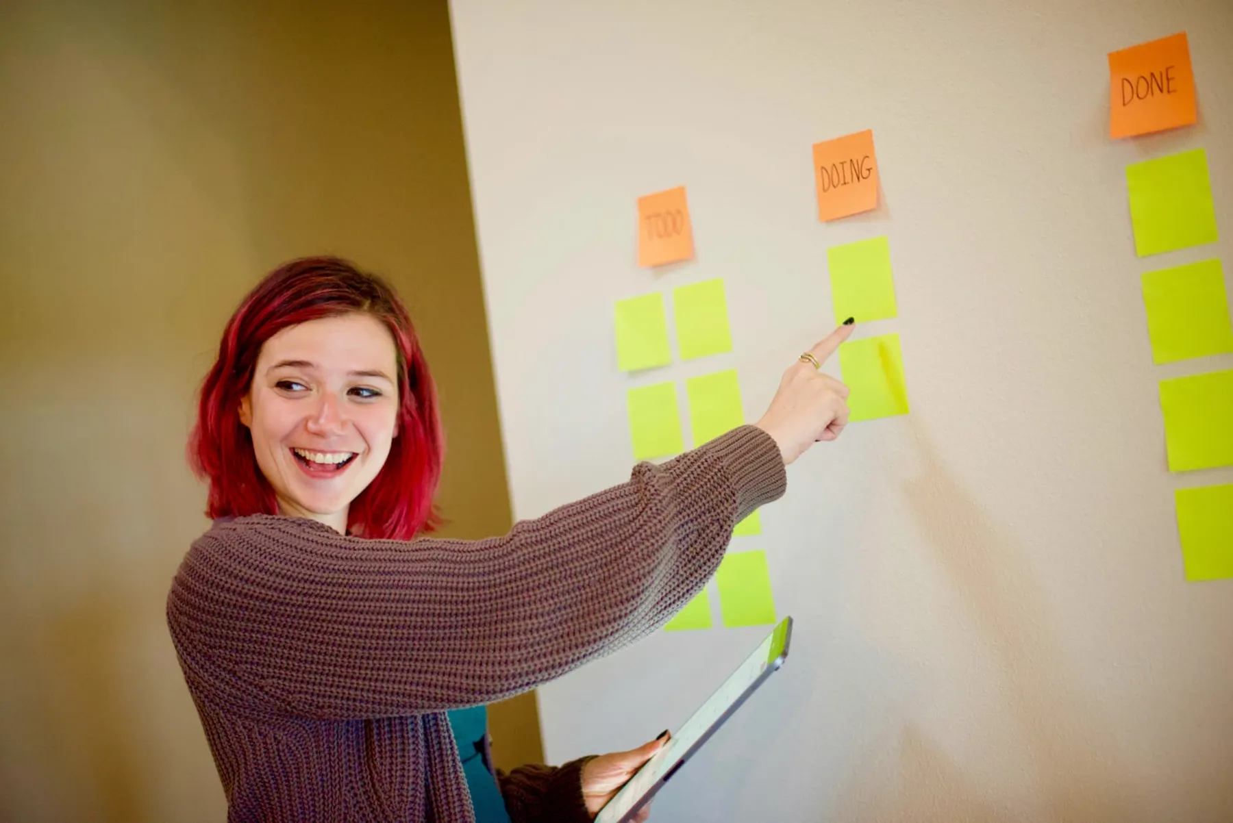 A facilitator smiling while moving sticky notes across a planning wall
