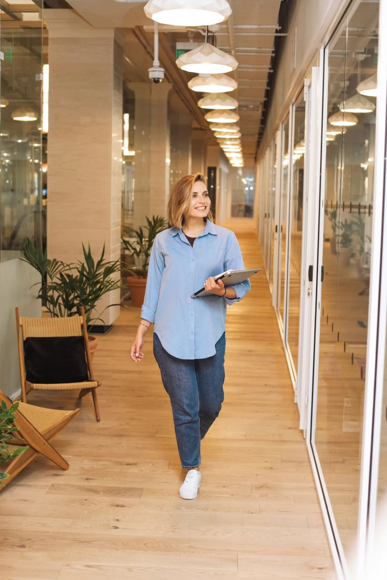 A woman walking through a light, plant-filled Nordic office
