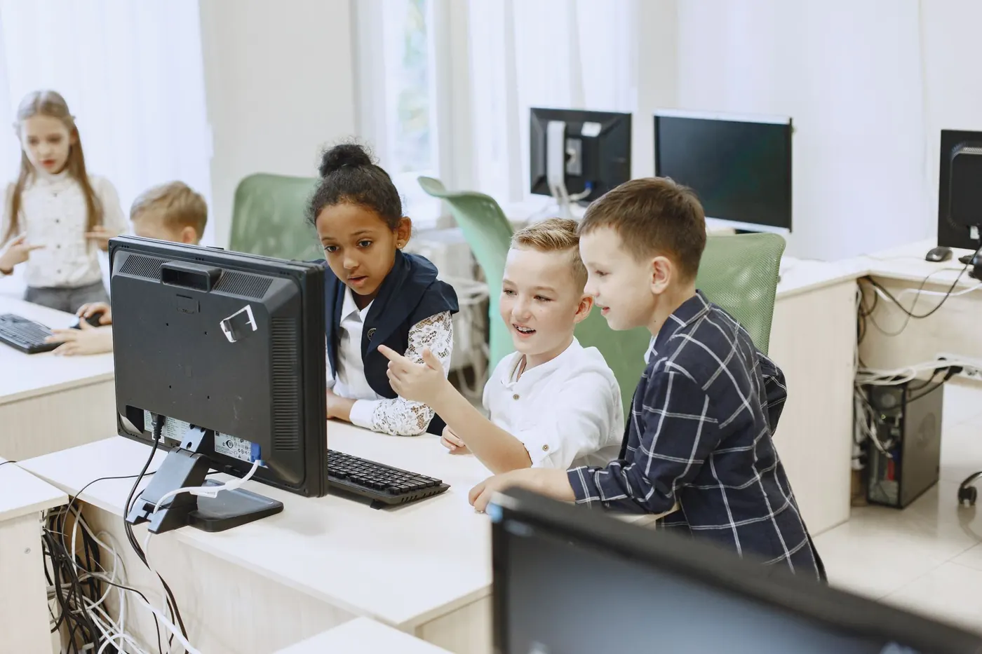 Young children exploring a computer together in an IT class