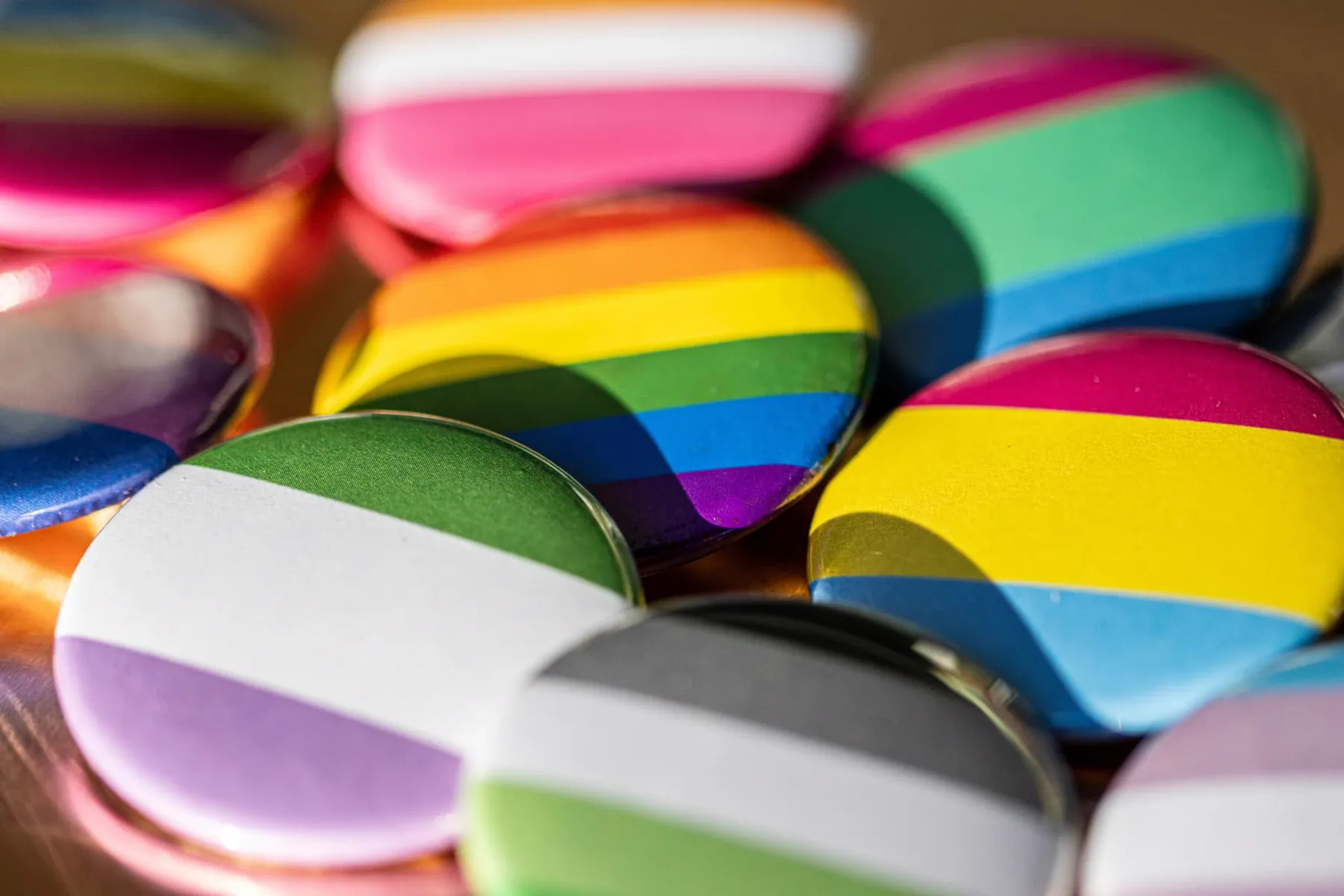 A close-up of colourful pin badges showing pride and identity flags